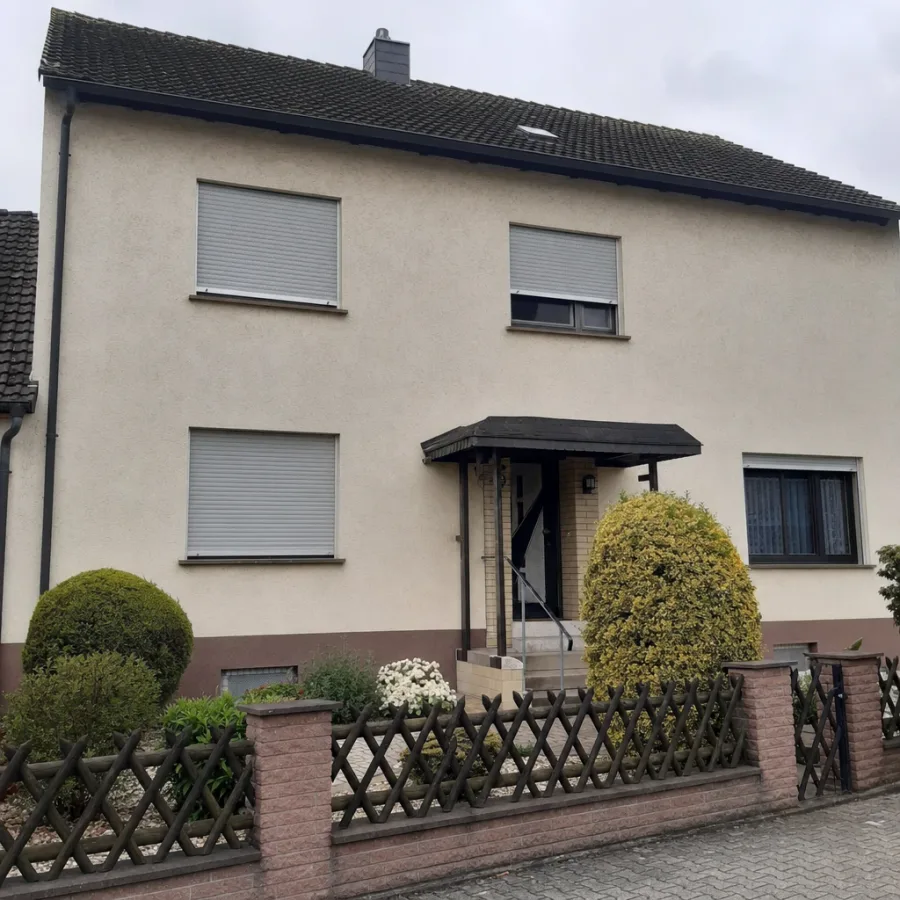 Handyfoto einer Einfamilienhaus-Fassade, frontal von der Straße aufgenommen