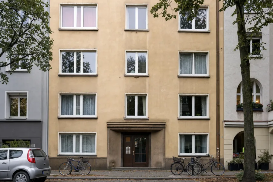 Mehrfamilienhaus aus den 1960er-Jahren mit Putzfassade und Fahrrädern vor dem Eingang
